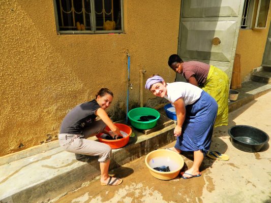 Drei Frauen waschen Wäsche in Schalen in Uganda