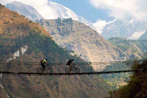 Zwei Radfahrer fahren über eine Hängebrücke