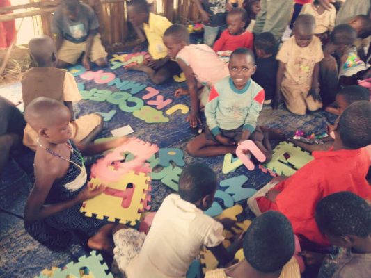 Viele Kinder spielen auf dem Boden mit Schaumstoffbuchstaben