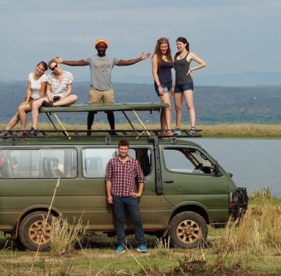 Fünf Personen stehen auf einem kleinen Bus und ein Mann steht davor