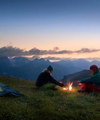 Tina Eckert sitzt mit einem Mann am Lagerfeuer