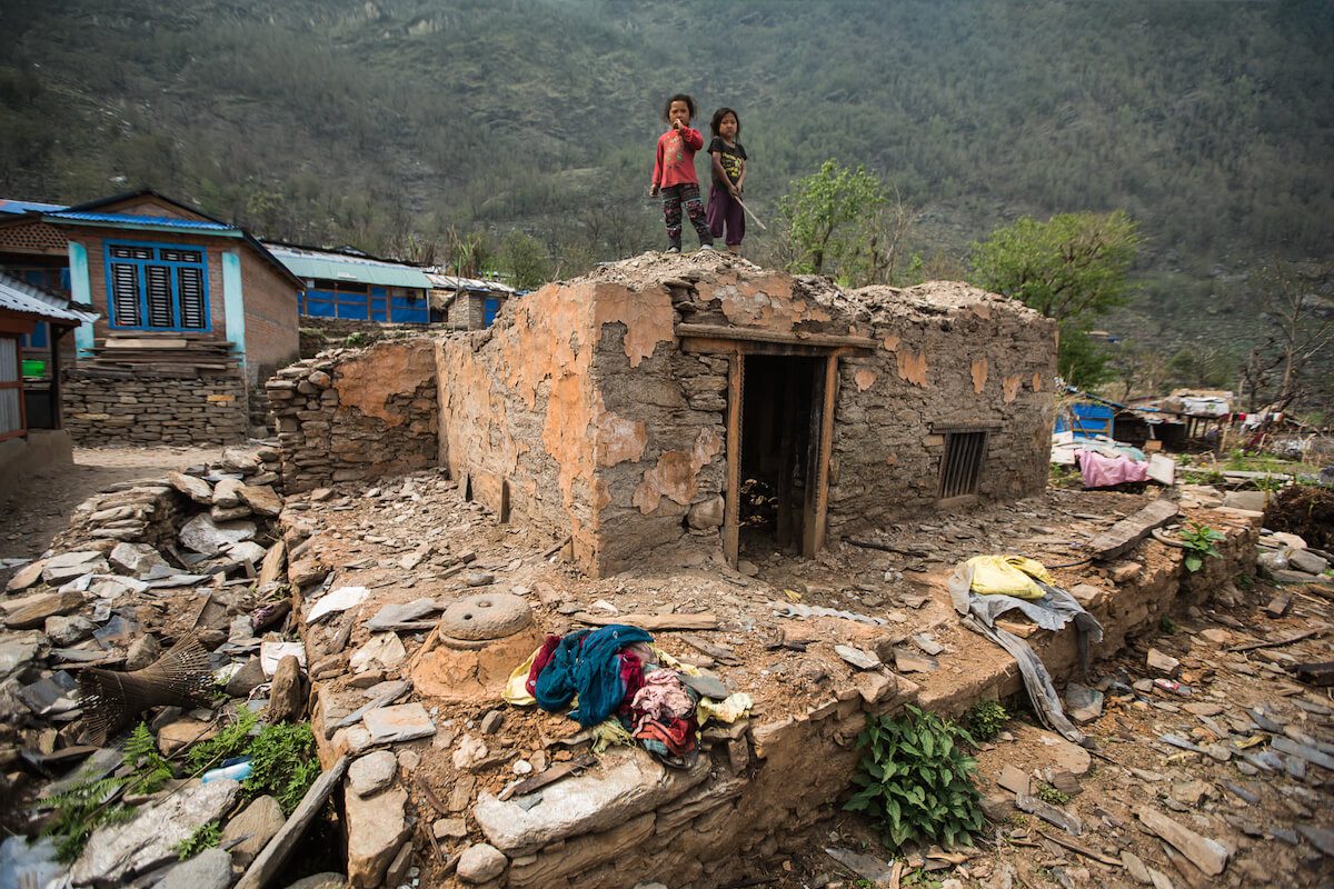 Zwei Kinder stehen auf einem zerstörten Haus