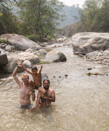 Zwei Männer baden mit Kind im Fluss