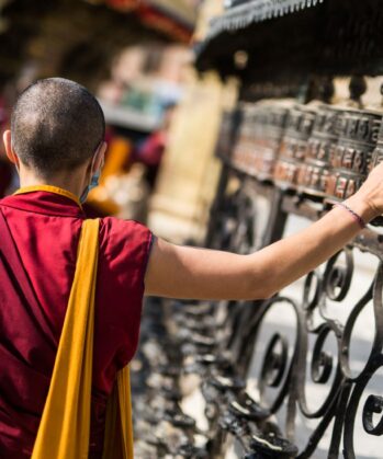 Mönch berührt Gebetsmühlen in Nepallen