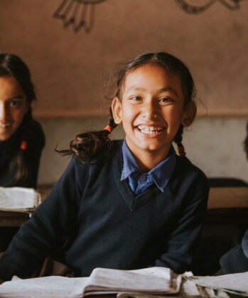 Lächelnde Schulmädchen sitzen im Klassenzimmer in Indonesien