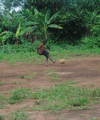 Ugandisches Kind schießt mit Fußball