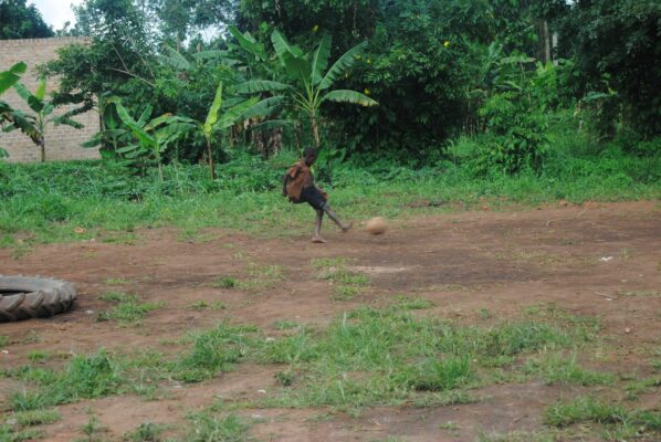 Ugandisches Kind schießt mit Fußball