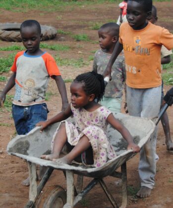 Kinder in Uganda spielen mit Schubkarren