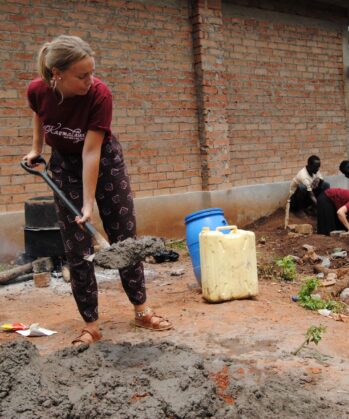 Volontärin mit Schaufel hilft in einem Bau-Workcamp in Uganda